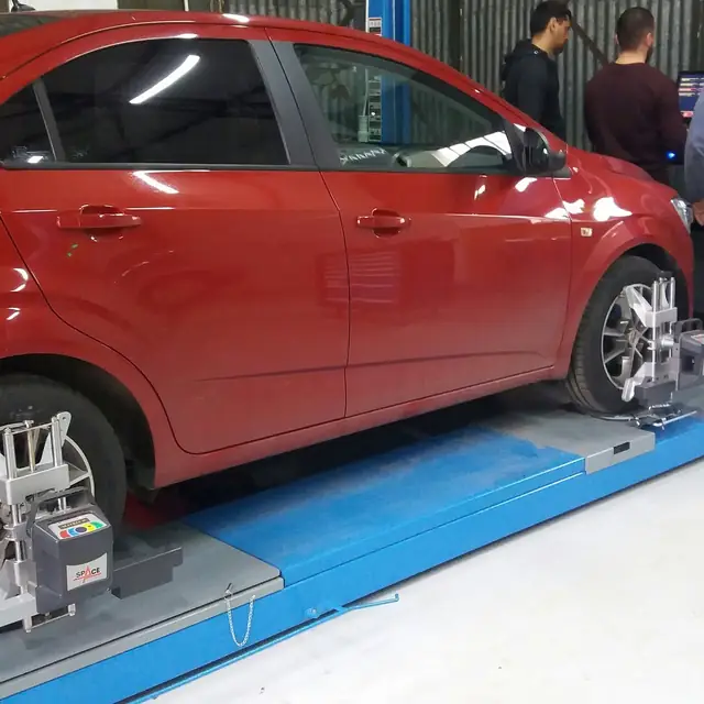 Autoturism roșu pe standul de geometrie 3D, cu țintele prinse pe roți